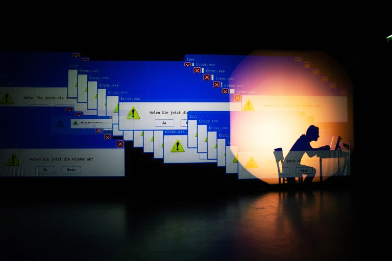 Szenenfoto aus "Ein Apartment auf dem Uranus". Der Schauspieler hinter einer Videoprojektion von Computermeldungen.