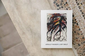 Weißer Katalog mit buntem Cover auf marmoriertem Steinboden