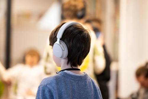Jungenkopf mit weißen Kopfhörern von hinten
