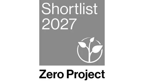 Zero Project logo: "Zero Project" written in white font against a gray background, and above an illustration of a green seedling breaking through a circle. Above this is the text "Shortlist 2027"