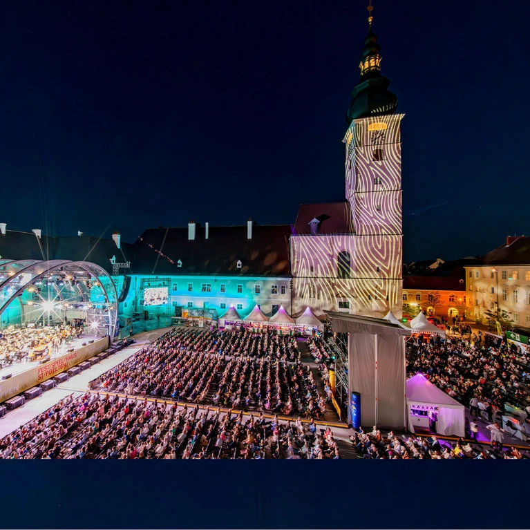 Photo of the Domplatz Open-Air concert featuring the Tonkünstler Orchestra – the stage can be seen on the left-hand side of the picture, along with the large crowd gathered against the backdrop of St. Pölten Cathedral.