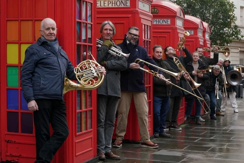 Foto vom London Brass Ensemble mit ihren Instrumenten zwischen den charakteristischen roten Londoner Telefonzellen.