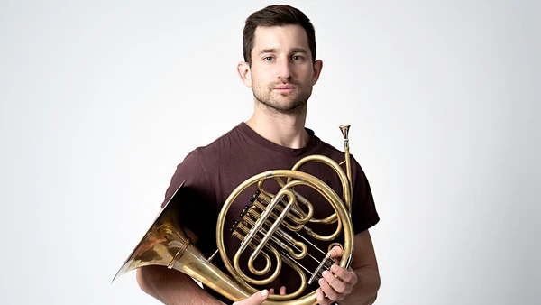 Portraitfoto von Sebastian Kolarz-Löschberger mit Horn