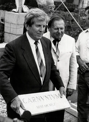 Grundsteinlegung 1989, LH Ludwig hält Carnuntumtafel in der Hand, auf Baustelle, herum andere Männer 