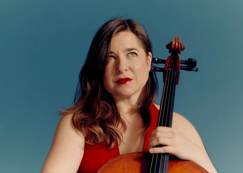 Foto von Alisa Weilerstein, Solistin mit dem Violoncello mit ihrem Instrument vor hellblauem Hintergrund.