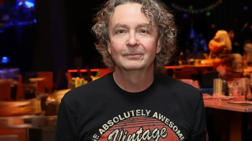 Mann mit grauen, halblangen Haaren vor unscharfem Hintergrund