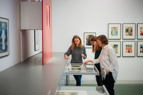 Raumansicht mit Personen in der Ausstellung Deix Archiv im Karikaturmuseum Krems im Jahr 2024