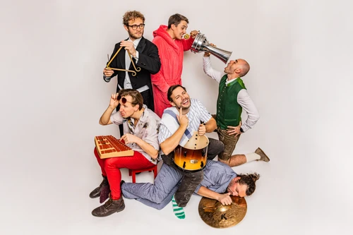 6 Musiker mit Schlaginstrumenten in witzigen Posen vor weißem Hintergrund