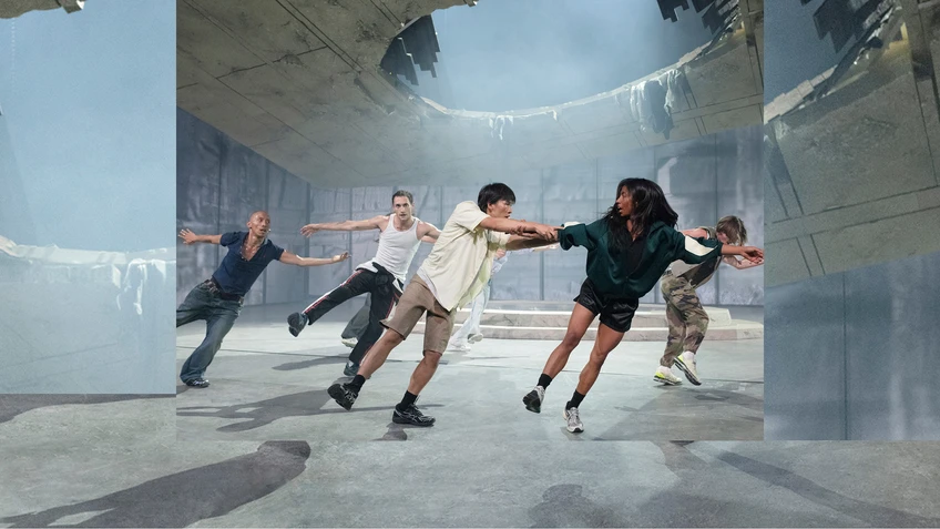 Szenenbild von "Aprés moi, le déluge", choreografiert vom Kollektiv (LA)HORDE und aufgeführt vom Ballet National de Marseille. Zu sehen sind in legérer Straßenkleidung eingekleidete Tänzer:innen, die gleichzeitig - schräg stehend - ein Bein zur Seite in der Luft haben.