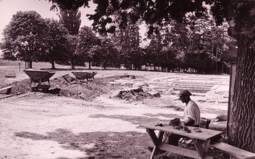 Grabung 1950 im Spaziergarten, Mann sitzt auf Bank vor den Ruinen 