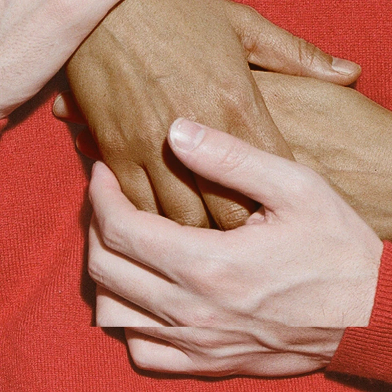 The theme for the Festspielhaus’s 2026/2027 season. The design features hands touching, a sleeve in a deep red colour against a red background created by the colour of the jumper.