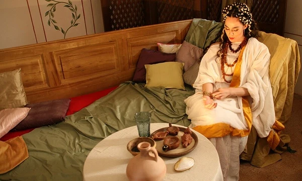 Reconstruction of a Roman living room with antique furniture and a person in historical clothing.