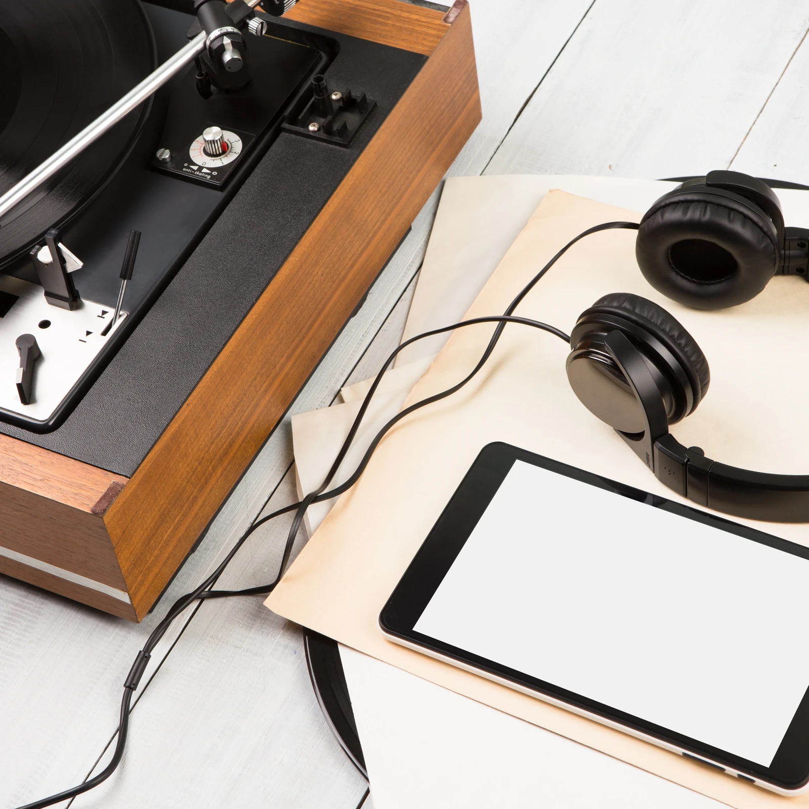 Ein Smartphone, Kopfhörer und ein Schallplattenspieler auf Holzboden