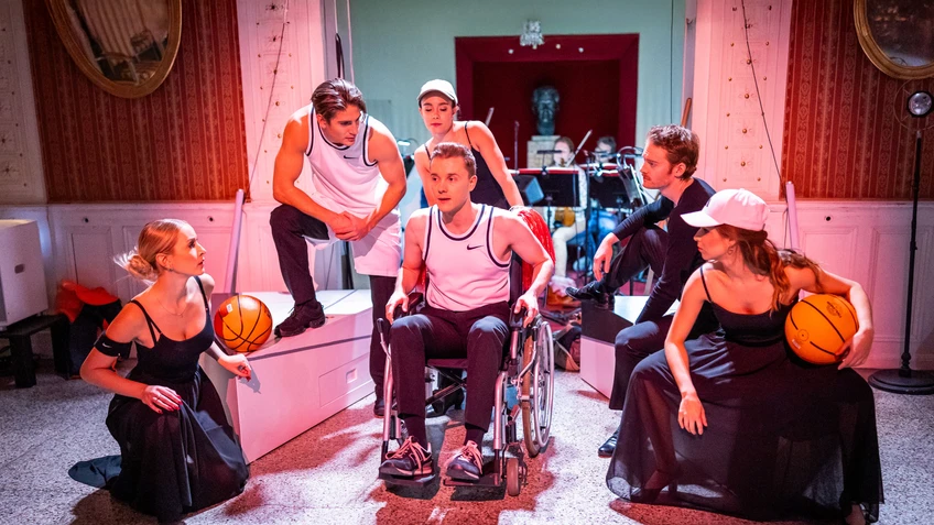 Fünf Personen umrunden eine im Rollstuhl sitzende sechste Person 