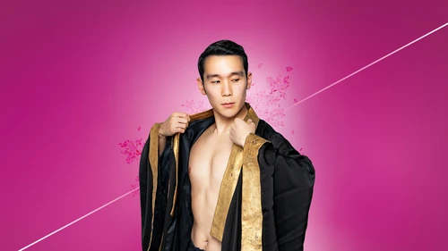 A person wearing a black robe with gold trim opens it slightly and looks sideways, set against a pink background with floating petals.
