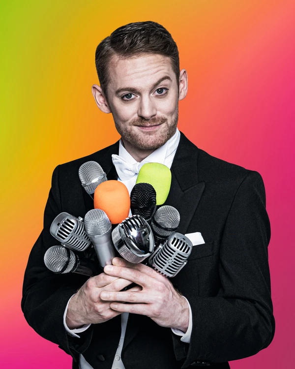 Man with many microphones in his hand. The background is green, yellow, orange, pink. Close-up.