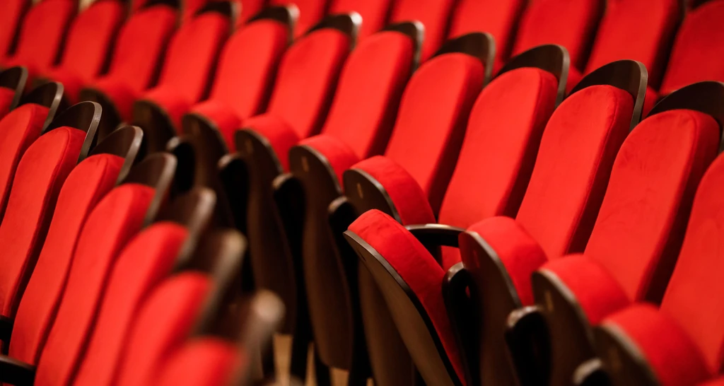 Reihen gepolsterter roter Theatersitze mit geschwungenen Rückenlehnen und dunklen Armlehnen.