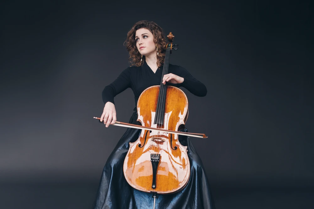 Junge Frau in dunkler Kleidung spielt Cello