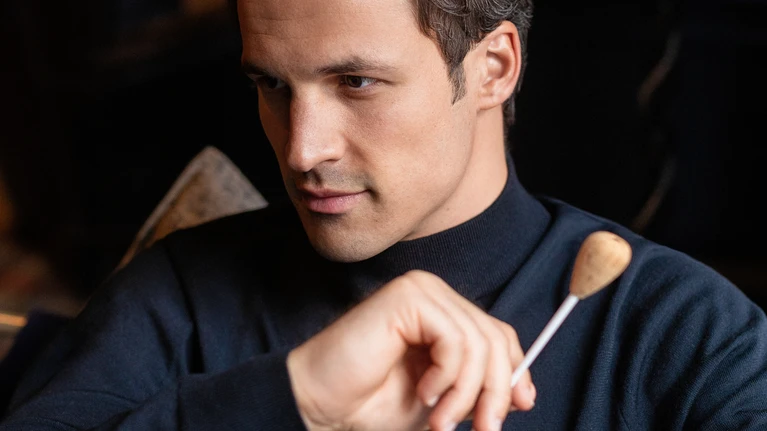 Portrait photo of conductor Andreas Otensamer with baton.