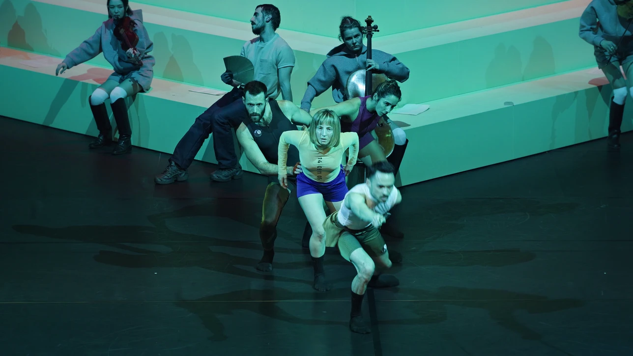 Das Videostill aus der Tanzperformance ‚Tournament‘ von Adam Linder und Ethan Braun mit dem Solistenensemble Kaleidoskop zeigt Tänzer:innen in dynamischer Bewegung auf einer hellen Bühne.