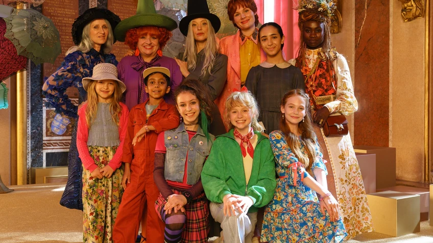 Kinder und Erwachsene in bunten Kostüme, als Gruppe zusammengestellt in einer Art Theaterkulisse