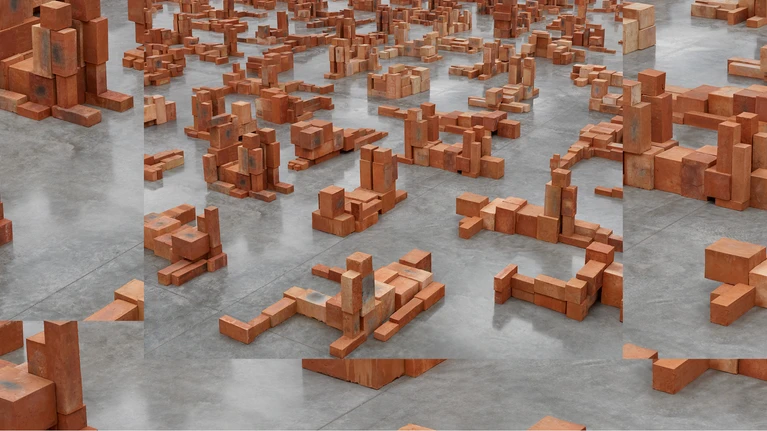 Photograph of Antony Gormley's installation ‘Resting Place II’ (2024), consisting of stacked terracotta stone blocks in a light grey gallery/museum space.