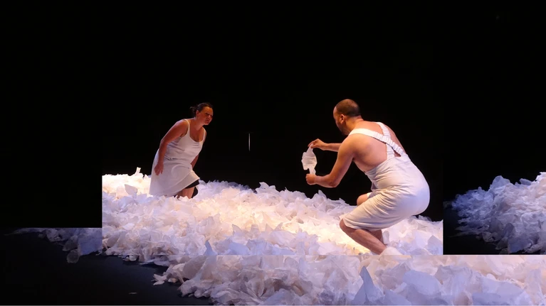 Szenenfoto aus "Sous la Neige / Unter dem Schnee" von der Compagnie Les Bestioles. Zu sehen sind zwei Performer:innen in weiß gekleidet, umgeben von weißen Papierfetzen.