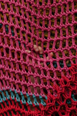 A child's hand reaches through the mesh structure of Toshiko Horiuchi MacAdam's colourful climbing installation at KinderKunstLabor.