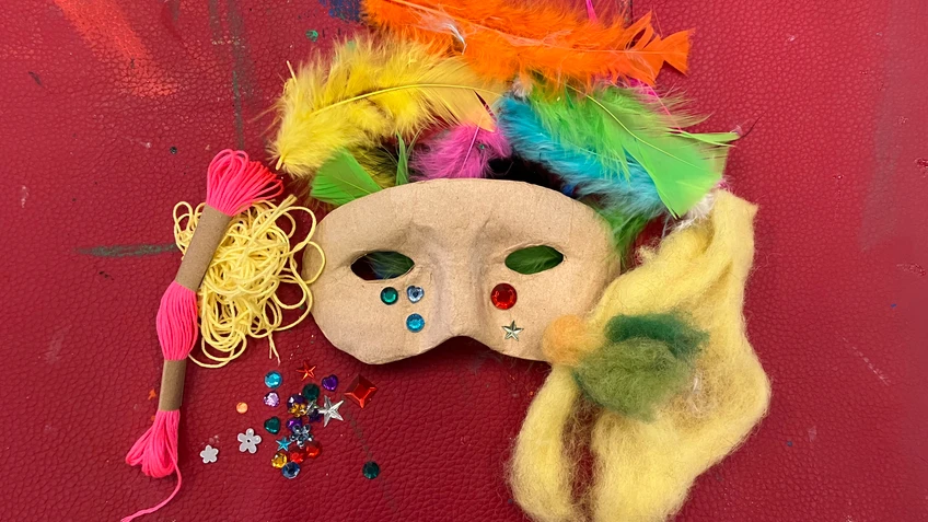 eine bunte Maske und Federn