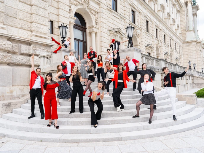 Gruppe von jungen Menschen gekleidet in rot, weiß und schwarz auf einer Treppe eines alten Gebäudes