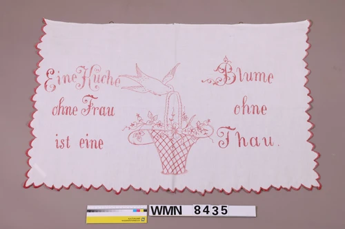 gestickter Wandschoner mit Text: Eine Küche ohne Frau ist eine Blume ohne Thau.