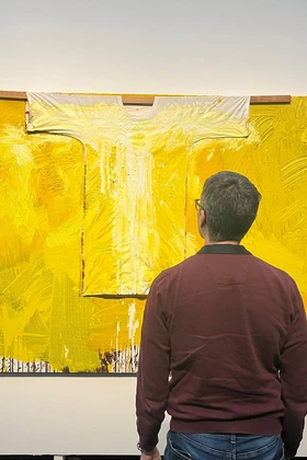 Two visitors look at a yellow artwork by Hermann Nitsch.