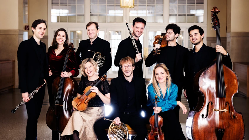 Eine Gruppe MusikerInnen  vor einer weißen Türe mit ihren Instrumenten