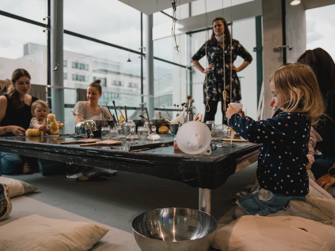 Photo from the BIG BANG Festival, showing children and adults working together at a kind of craft table.