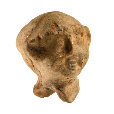 A doll's head with a round face and protruding ears. Inside the head are small stones that make a rattle-like sound when shaken. Traces of red paint; worn surface.