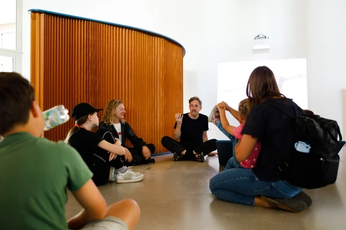 Artist Kay Walkowiak sits in the exhibition space of the KinderKunstLabor and chats with workshop participants.