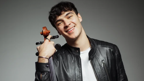 Junger Mann in Lederjacke lehnt sich an ein Cello