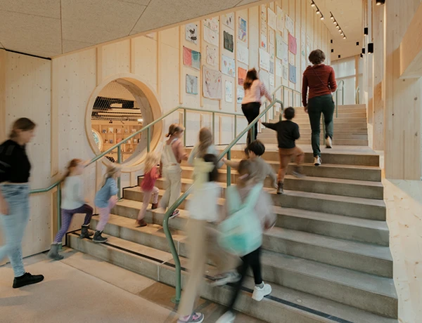 Eine Gruppe von Besucher:innen geht im KinderKunstLabor das hölzerne Stiegenhaus empor.