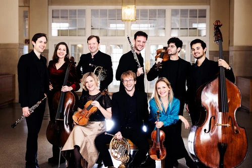 Eine Gruppe MusikerInnen  vor einer weißen Türe mit ihren Instrumenten