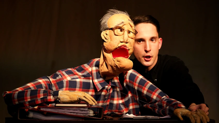 Szenenbild: Mann mit Handpuppe.