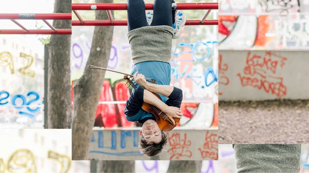 Foto für die Performance "Fledermäuse", zu sehen ist ein:e Künstler:in des Kollektivs "schallundrauch agency" der:die kopfüber von einem Klettergerüst hängt, mit den Armen eine Geige fest umschließend.Foto für die Performance "Fledermäuse", zu sehen ist ein:e Künstler:in des Kollektivs "schallundrauch agency" der:die kopfüber von einem Klettergerüst hängt, mit den Armen eine Geige fest umschließend.v