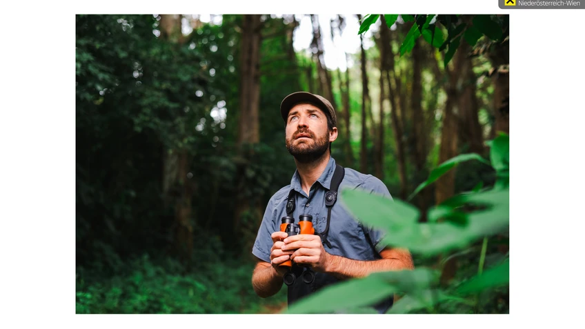 Ein Mann schaut nach oben mit Fernglas in der Hand. 