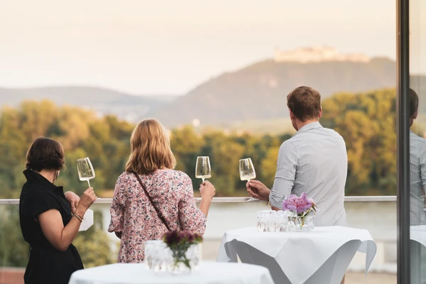 Three people with wine glasses and their backs to the camera on the Landesgalerie terrace