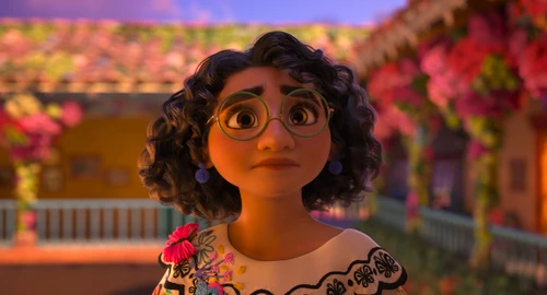 Ein dunkel gelocktes Mädchen mit Brille vor einem Haus, das mit Blumen geschmückt ist