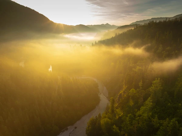 Sonnenaufgang im Lassingtal, zu sehen sind Wälder und Berge im aufgehenden Licht der Sonne. 