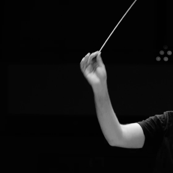 A hand holding a conductor's baton