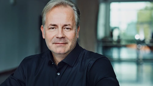 Mann mit grauem Haar und dunkelblauem Hemd