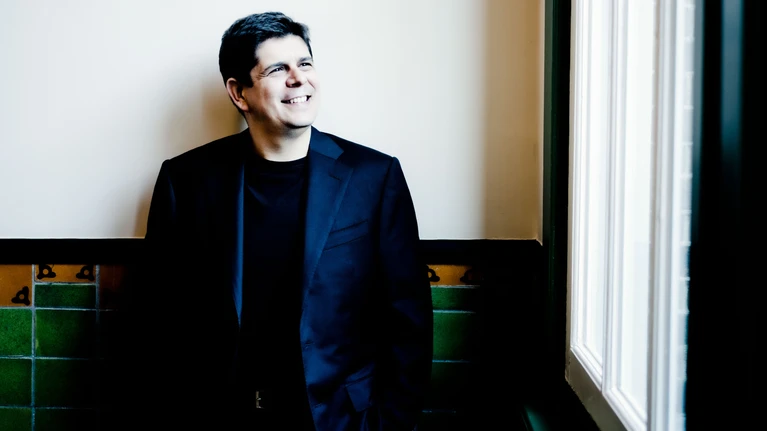 Photo of pianist Javier Perianes, seen wearing a black suit with a black shirt underneath. 