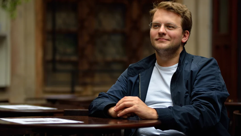 Mann in dunkler Jacke mit Brille am Klavier