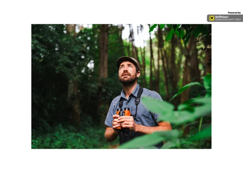 Ein Mann schaut nach oben mit Fernglas in der Hand. 